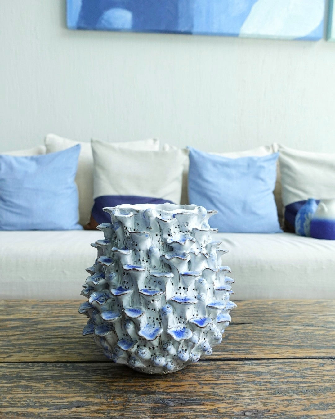 Decorative vase on a wooden table with a couch and pillows in the background