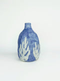 Blue ceramic vase with white abstract patterns on a light gray background
