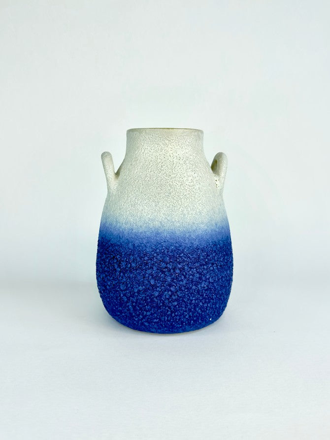 Ceramic vase with gradient blue and white design on a light gray background